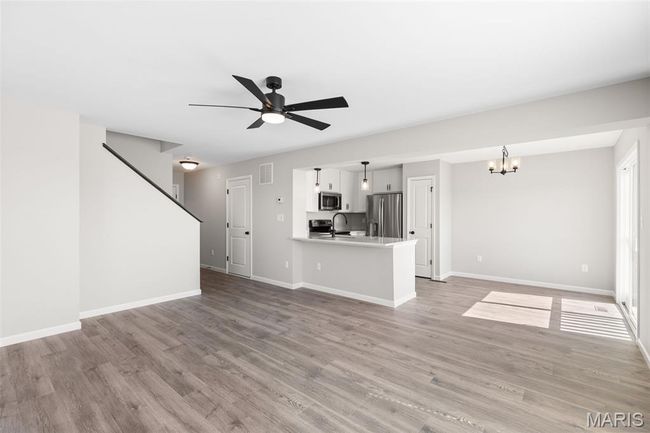 Unfurnished living room with ceiling fan, a chandelier, light wood-style flooring, and baseboards | Image 7