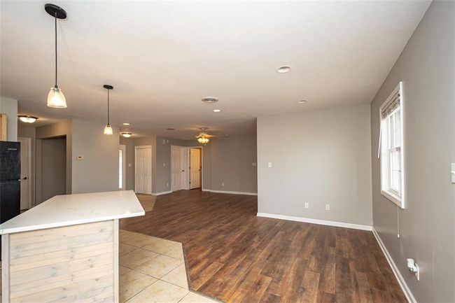 Kitchen with a ceiling fan, a kitchen island, wood finished floors, light countertops, and baseboards | Image 21