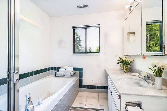 Bathroom featuring vanity, tile patterned flooring, and a relaxing tiled tub | Image 7