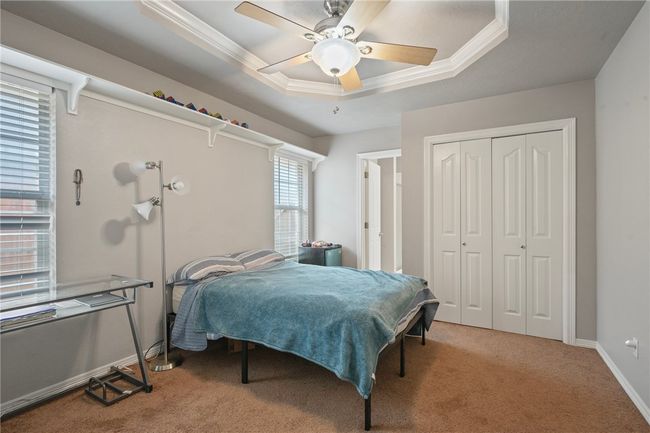 Carpeted bedroom featuring a tray ceiling, a closet, crown molding, ceiling fan, and baseboards | Image 10