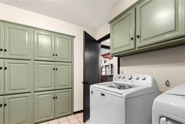 Laundry area featuring light tile patterned floors, cabinet space, and independent washer and dryer | Image 21
