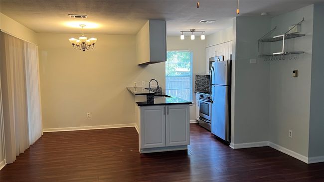 Kitchen featuring a sink, appliances with stainless steel finishes, a chandelier, dark wood finished floors, and dark countertops | Image 4