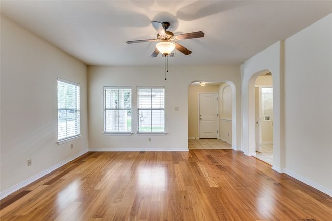 Empty room with arched walkways, a ceiling fan, and light wood finished floors | Image 6