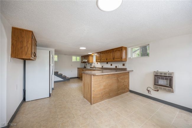 Kitchen featuring freestanding refrigerator, heating unit, a peninsula, a sink, and brown cabinets | Image 20