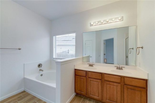 Bathroom with a bath, double vanity, wood finished floors, and baseboards | Image 11
