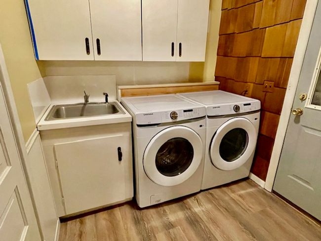 Laundry area with washing machine and clothes dryer, sink, cabinets, and light wood-type flooring | Image 19
