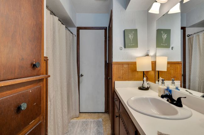 Full bath featuring vanity, a wainscoted wall, wooden walls, and a shower with shower curtain | Image 18