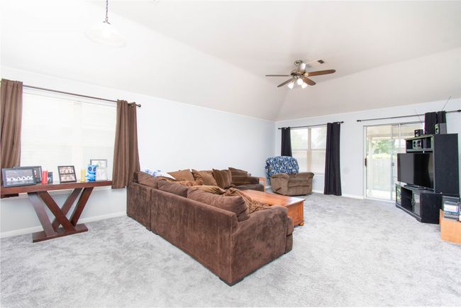 Living area featuring carpet flooring, baseboards, lofted ceiling, and ceiling fan | Image 5