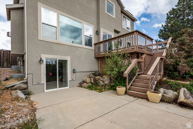 Back of property with stucco siding, a patio, a wooden deck, and stairs | Image 32