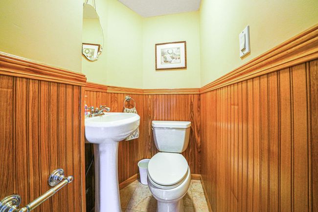 Half bathroom with a sink, a wainscoted wall, toilet, and tile patterned flooring | Image 13