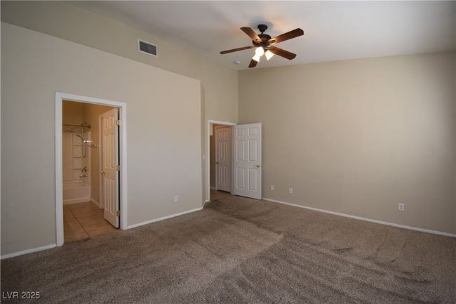 Unfurnished bedroom with a ceiling fan, ensuite bathroom, carpet floors, baseboards, and visible vents | Image 21