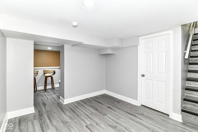 finished below grade area with stairs, wood finished floors, and baseboards | Image 32