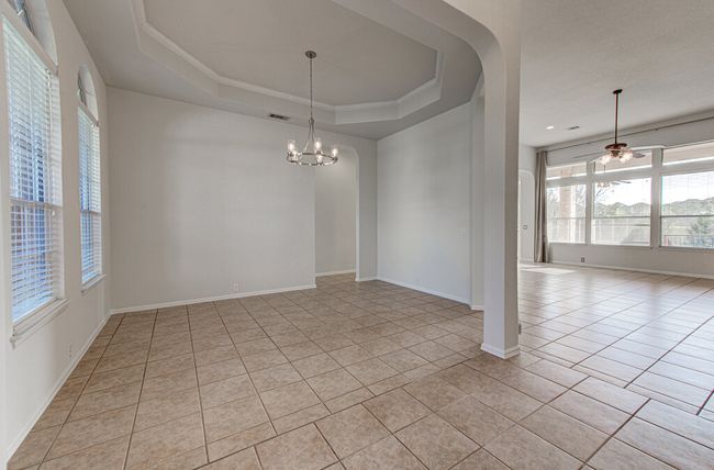 Unfurnished room featuring a tray ceiling, light tile patterned flooring, baseboards, and visible vents | Image 6