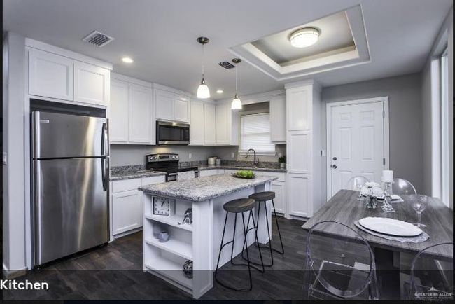 Kitchen with visible vents, appliances with stainless steel finishes, white cabinets, a raised ceiling, and open shelves | Image 4