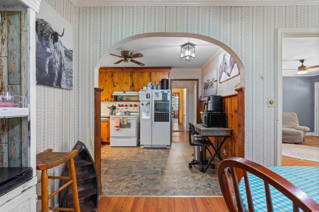 Kitchen with white appliances, ceiling fan, arched walkways, wallpapered walls, and crown molding | Image 15