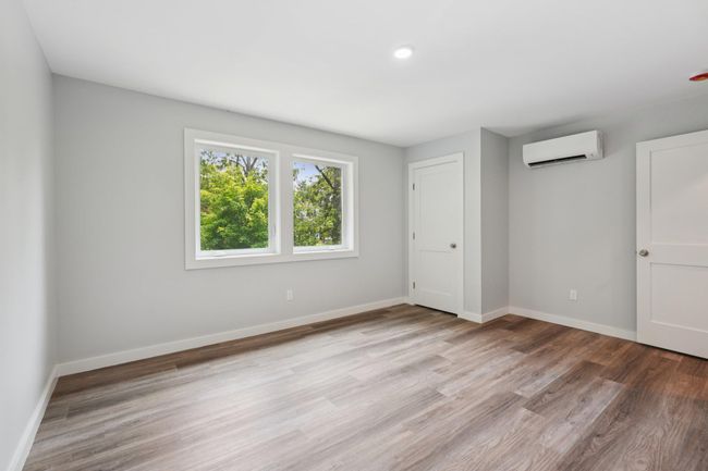 Bedroom with a wall unit AC and wood finished floors | Image 15