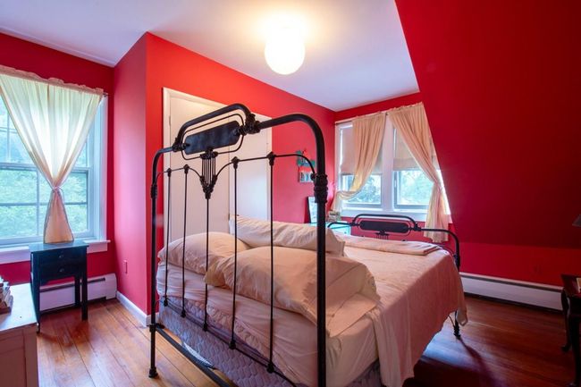 Bedroom with baseboard heating, a baseboard radiator, baseboards, and wood finished floors | Image 9