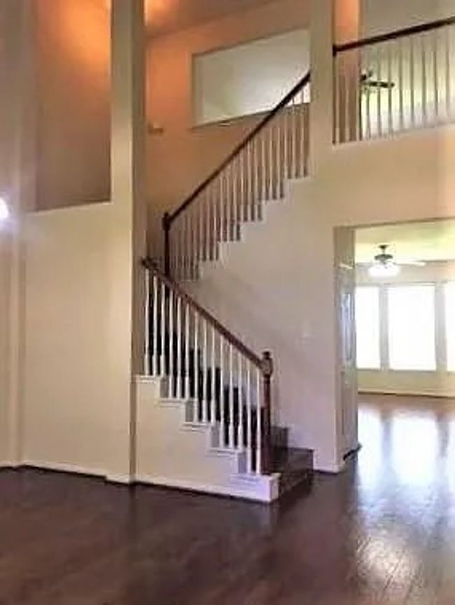 Staircase featuring a towering ceiling, a ceiling fan, and wood finished floors | Image 8