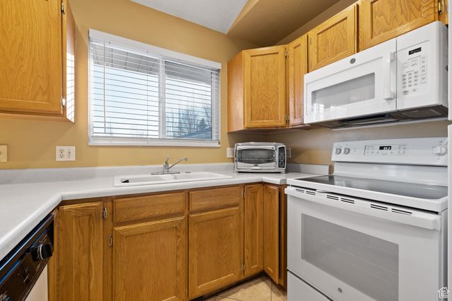 Kitchen featuring sink, light tile patterned floors, and white appliances | Image 11