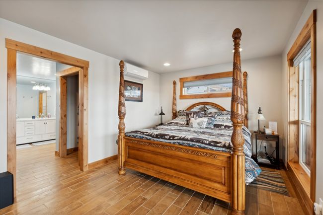 Bedroom featuring an inviting chandelier, ensuite bath, a wall mounted AC, and multiple windows | Image 49