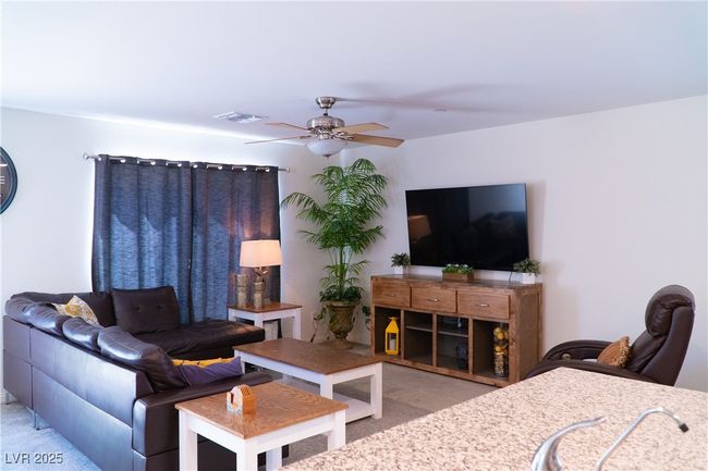 Carpeted living room featuring a ceiling fan and visible vents | Image 29