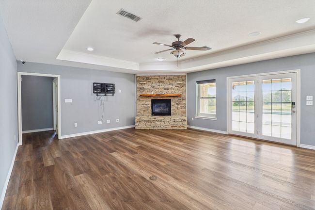 Unfurnished living room featuring visible vents, wood finished floors, a ceiling fan, and a raised ceiling | Image 11