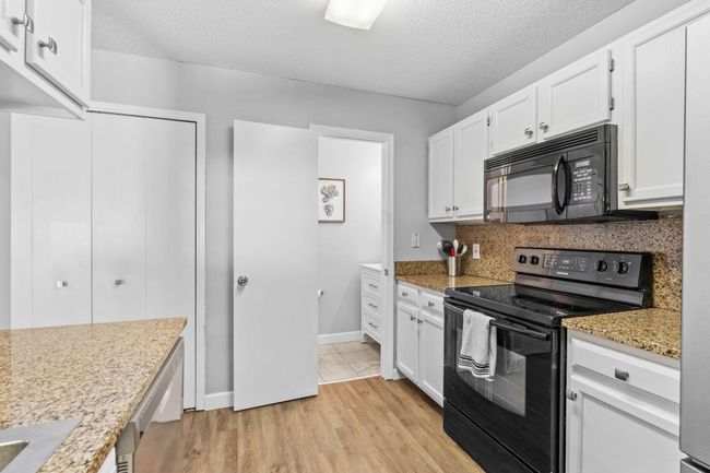 Functional kitchen layout with abundant cabinet space, granite counters, and convenient access to the half bath. | Image 11