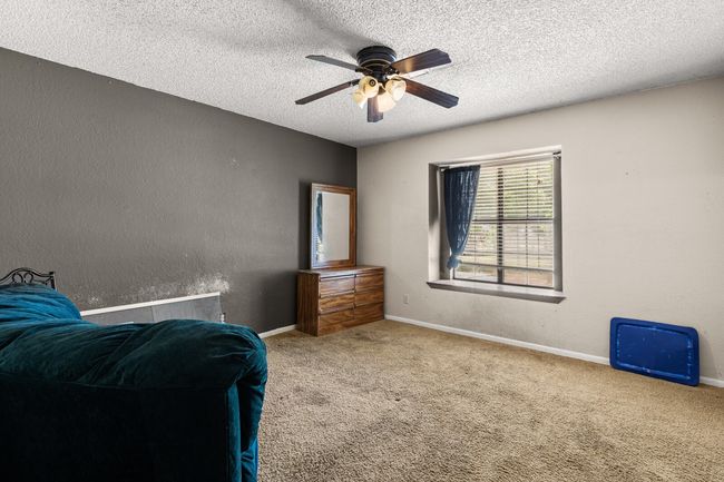 Bedroom with a textured ceiling, baseboards, carpet, ceiling fan, and a textured wall | Image 15