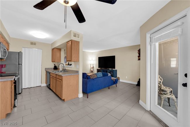 Kitchen featuring stainless steel microwave, light countertops, dishwasher, visible vents, and open floor plan | Image 7