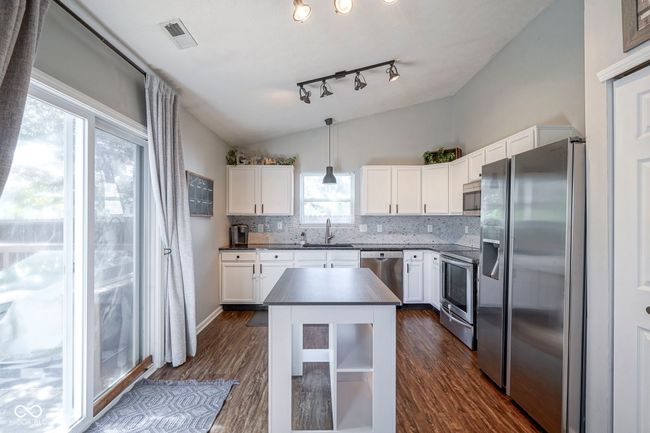 kitchen featuring appliances with stainless steel finishes, dark countertops, a sink, dark wood-style floors, and lofted ceiling | Image 12