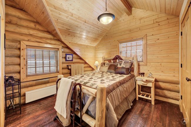 Bedroom with radiator, dark wood-type flooring, log walls, and wooden ceiling | Image 25