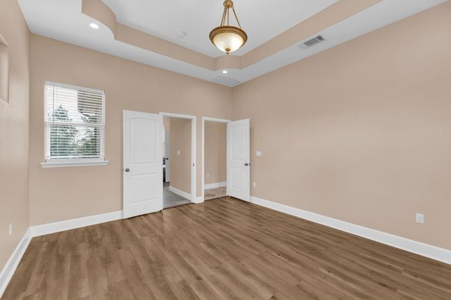 Unfurnished bedroom with wood finished floors, a raised ceiling, and recessed lighting | Image 18