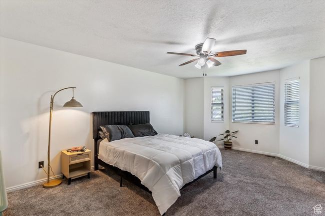 Bedroom featuring a textured ceiling, carpet flooring, baseboards, and a ceiling fan | Image 12