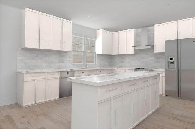 Kitchen with wall chimney exhaust hood, stainless steel refrigerator with ice dispenser, a center island, and backsplash | Image 5