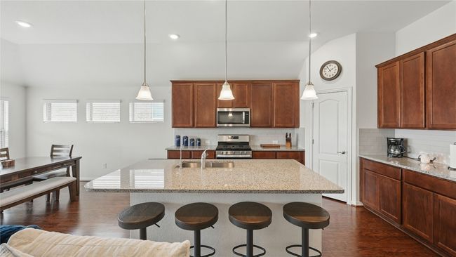 Kitchen with appliances with stainless steel finishes, a kitchen breakfast bar, dark wood-type flooring, lofted ceiling, and tasteful backsplash | Image 17
