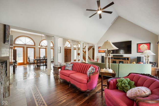 living area with wood finished floors, high vaulted ceiling, ceiling fan, and decorative columns | Image 9