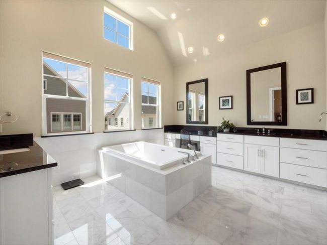 Bathroom featuring marble tiled floors, two vanities, a bath, lofted ceiling, and recessed lighting | Image 11