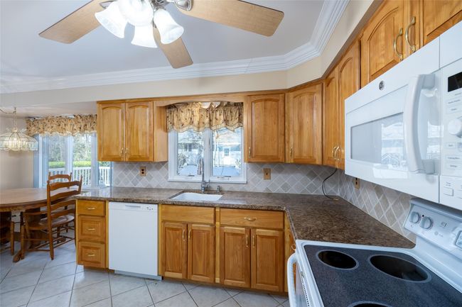 Kitchen featuring white appliances, backsplash, ornamental molding, and a sink | Image 16