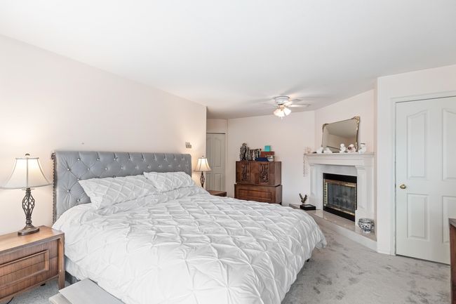 Bedroom featuring light colored carpet, a glass covered fireplace, and a ceiling fan | Image 22
