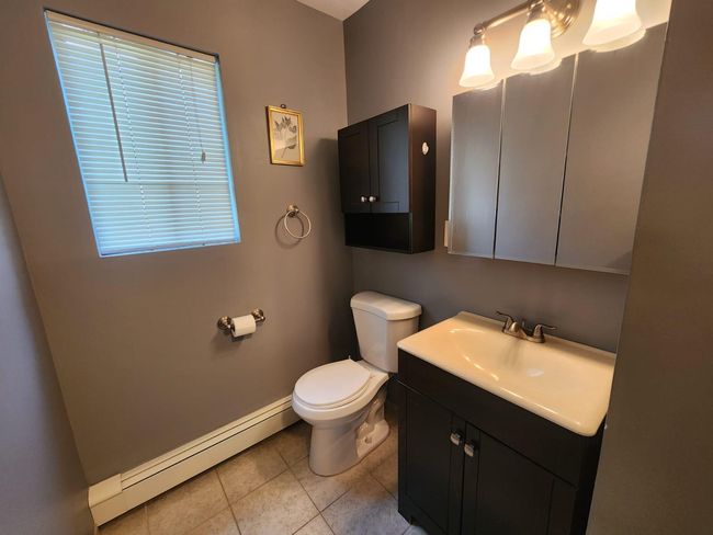 Half bath with a baseboard radiator, tile patterned floors, and vanity | Image 8