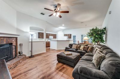 Living room featuring Luxury vinyl plank / wood-style floors, a brick fireplace, ceiling fan, and vaulted ceiling | Image 3