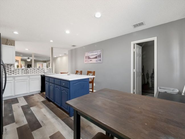 Kitchen featuring a center island, kitchen peninsula, a kitchen bar, white cabinets, and blue cabinets | Image 10