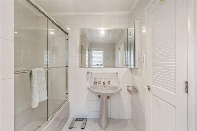 Bathroom featuring tile walls, crown molding, and shower / bath combination with glass door | Image 24