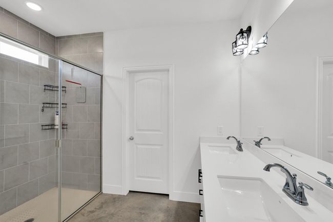 Full bath with tiled shower, concrete floors, double vanity, and recessed lighting | Image 29
