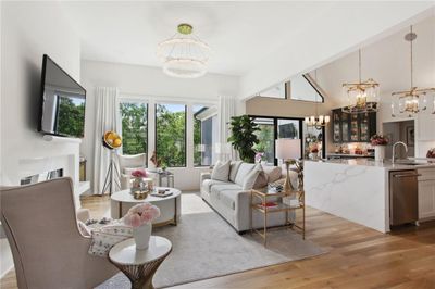 Living room featuring a chandelier, a towering ceiling, and light wood-type flooring | Image 2