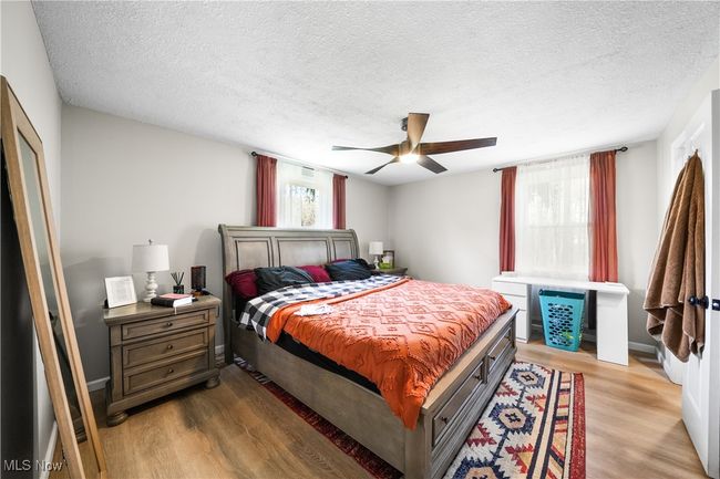 Bedroom with a textured ceiling, ceiling fan, light wood-style flooring, and baseboards | Image 11