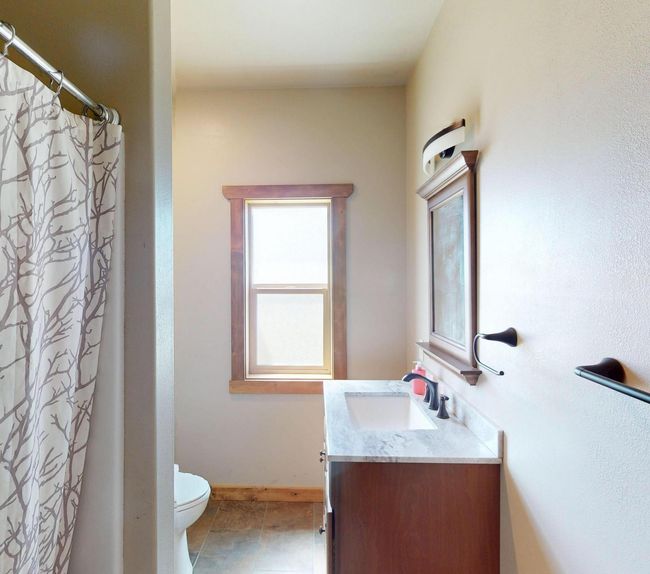 Bathroom featuring a shower with curtain, baseboards, toilet, tile patterned floors, and vanity | Image 16