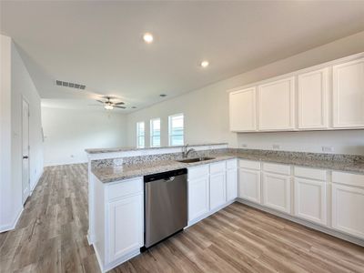 Kitchen includes granite countertops, luxury vinyl plank flooring, 36” upper cabinets with crown molding, a full suite of stainless-steel Whirlpool appliances – including refrigerator with ice maker, recessed lighting, and a large single basin sink. | Image 3