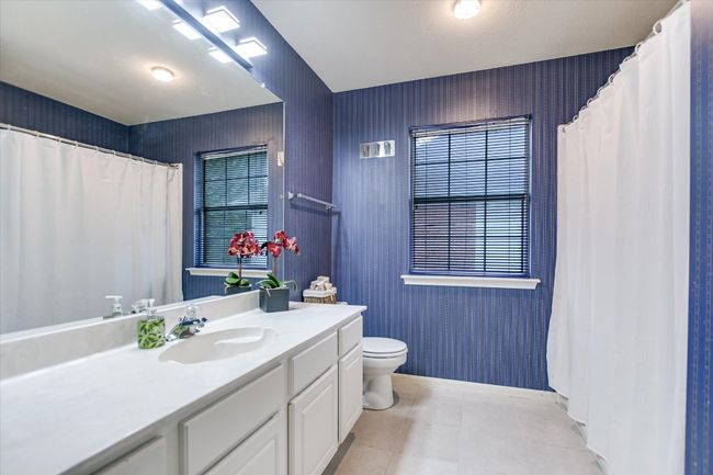 Bathroom with toilet, vanity, wallpapered walls, tile patterned flooring, and curtained shower | Image 14