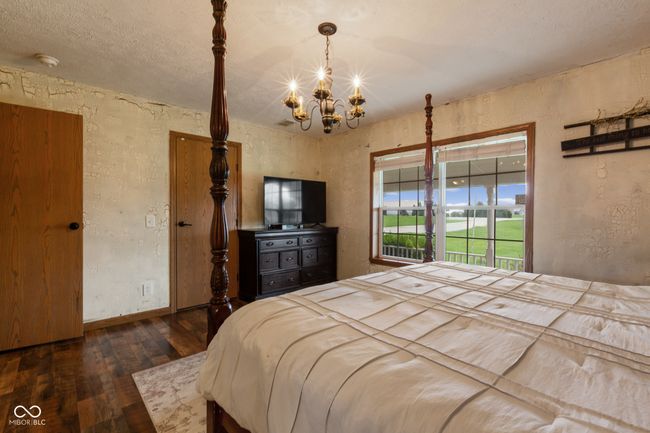 unfurnished bedroom with a chandelier, hardwood / wood-style floors, a textured wall, and baseboards | Image 34